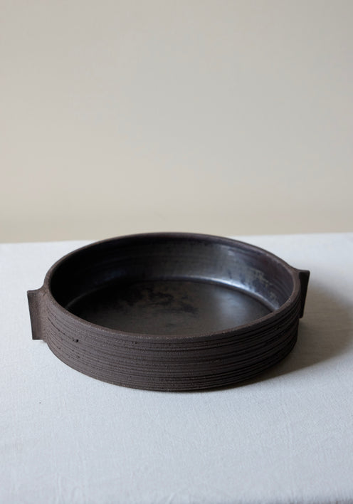 Carved Ceramic Serving Plate | soil, a low, circular dish with integral handles, showcasing Alex Gabriels' rough finish and carved lines, 27.5cm wide.