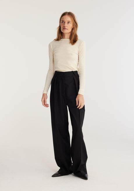 Fine merino long sleeve | off-white: Model in fitted cream merino wool top, long sleeves, crew neck, paired with high-waisted black trousers and pointed-toe shoes.