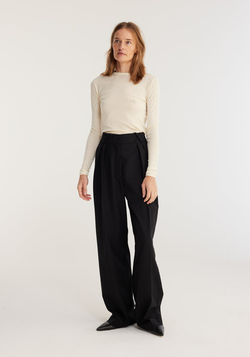 Fine merino long sleeve | off-white: Model in fitted cream merino wool top, long sleeves, crew neck, paired with high-waisted black trousers and pointed-toe shoes.