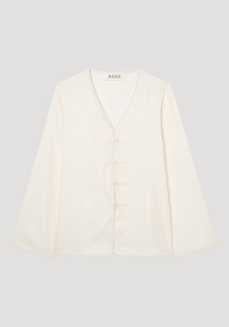Mandarin silk top in cream with long sleeves, V-neck, embroidered edges, and four frog-style pankou closures, showcasing a relaxed fit ideal for layering.