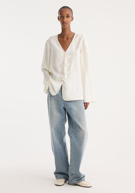 Mandarin silk top in cream with long sleeves, V-neck, embroidered edges, and four frog-style pankou closures, showcasing a relaxed fit ideal for layering.