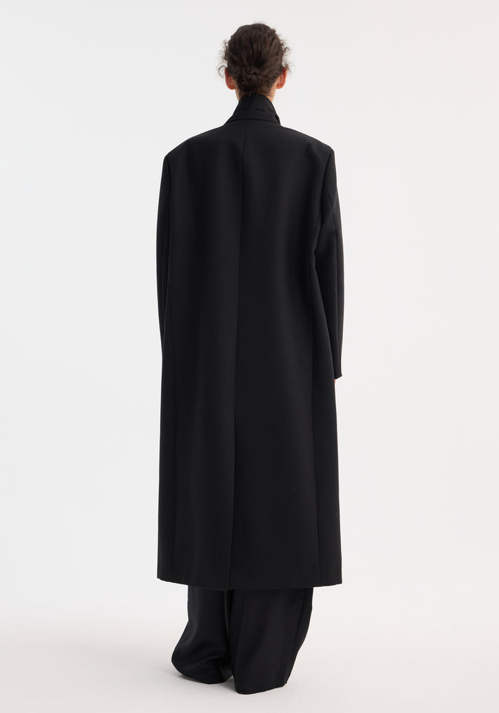 Back view of a person wearing the Signature opera coat | black, a long, tailored overcoat with sleek lapels, a center back slit, and welt pockets.