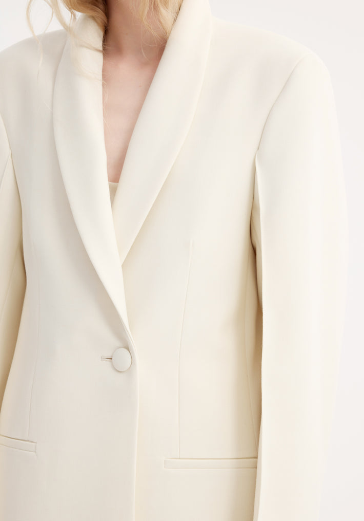 Close-up of a women’s ivory Signature opera coat with a shawl lapel, single fabric-covered button, and welt pockets, showcasing an elegant tailored design.