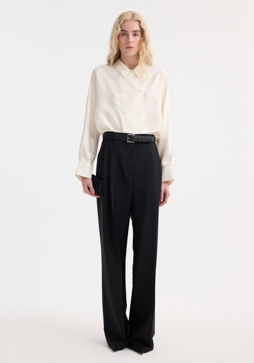 Model wearing a Relaxed fit button down top | cream, featuring double-breasted button closure, pointed collar, tucked into high-waisted wide-leg trousers.