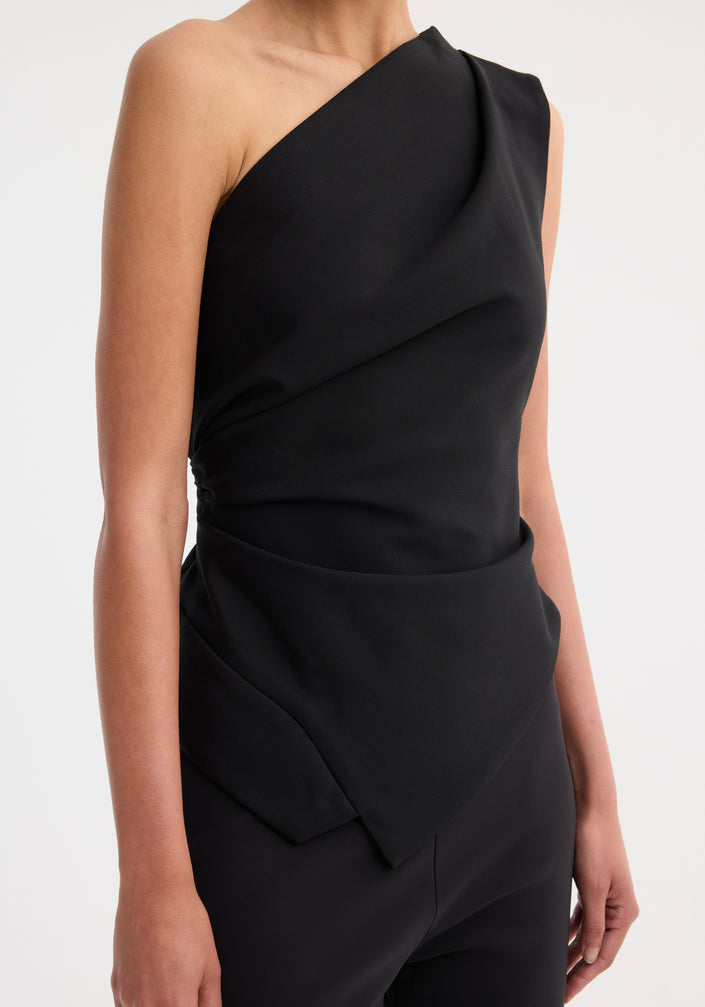 Model wearing the Off-shoulder lapel top | black, featuring an asymmetrical design with a fitted waist, paired with slim-fit trousers and strappy nude sandals.