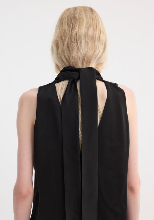 Model in a sleeveless draped satin top with a cowl neckline and wide-leg trousers, showcasing a minimalist, fluid silhouette.