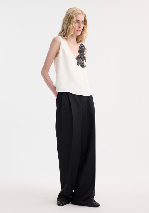 Slim woman in a Scoop-neck silk lace top with intricate black floral lace on shoulder, paired with high-waisted trousers. Perfect for minimalist wardrobes.