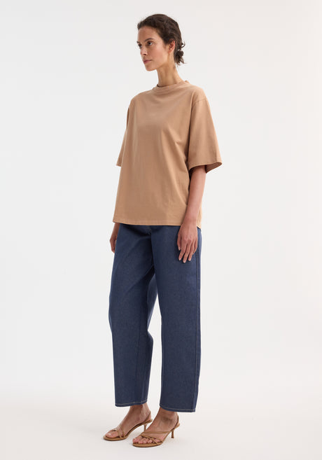 Model wearing an Oversized cotton t-shirt | powder with short sleeves and a high-waisted, wide-leg denim jeans, showcasing a minimalist, relaxed style.
