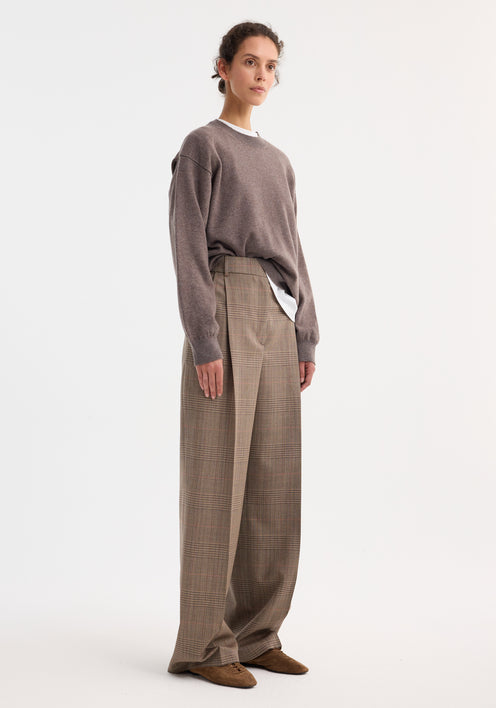 Model wears Mid-waist tailored trousers | Prince of Wales, showcasing high-waisted, wide-leg design, double pleats, and tailored waistband, paired with taupe sweater and brown suede shoes.