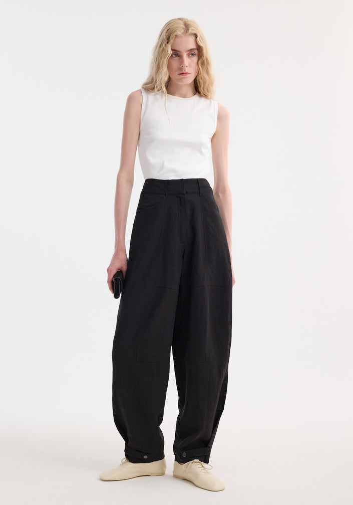 Model in Parachute trousers | black, featuring high-waisted, wide-leg design with tapered cuffs, paired with a rib-knit top and beige lace-up shoes.