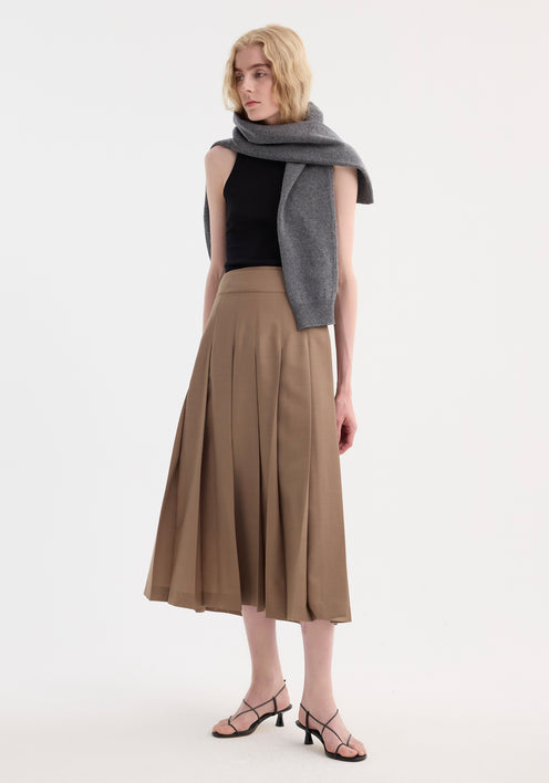 Model wearing Plissé wrap skirt in khaki with all-over pleats and wrap waistband, styled with a black tank top, grey sweater, and black sandals.
