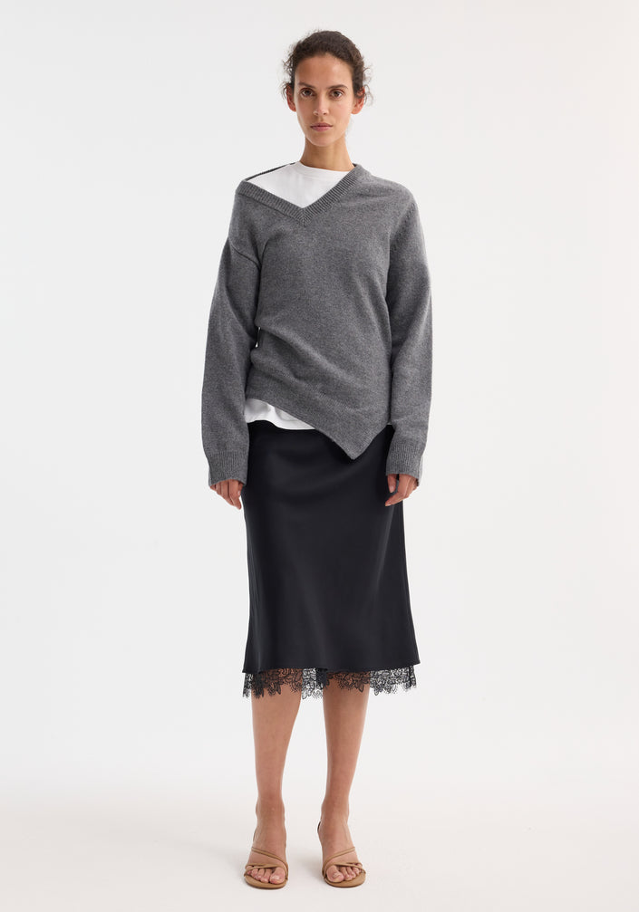 Woman wearing Lace-trimmed silk skirt | black, featuring delicate lace at hem, paired with a heather-gray V-neck sweater.