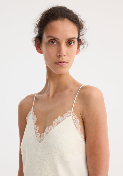 Model wearing Lace slipdress | cream, featuring a full-length design with lace-trimmed V-neck, ultra-thin spaghetti straps, and flowing silhouette, paired with tan sandals.