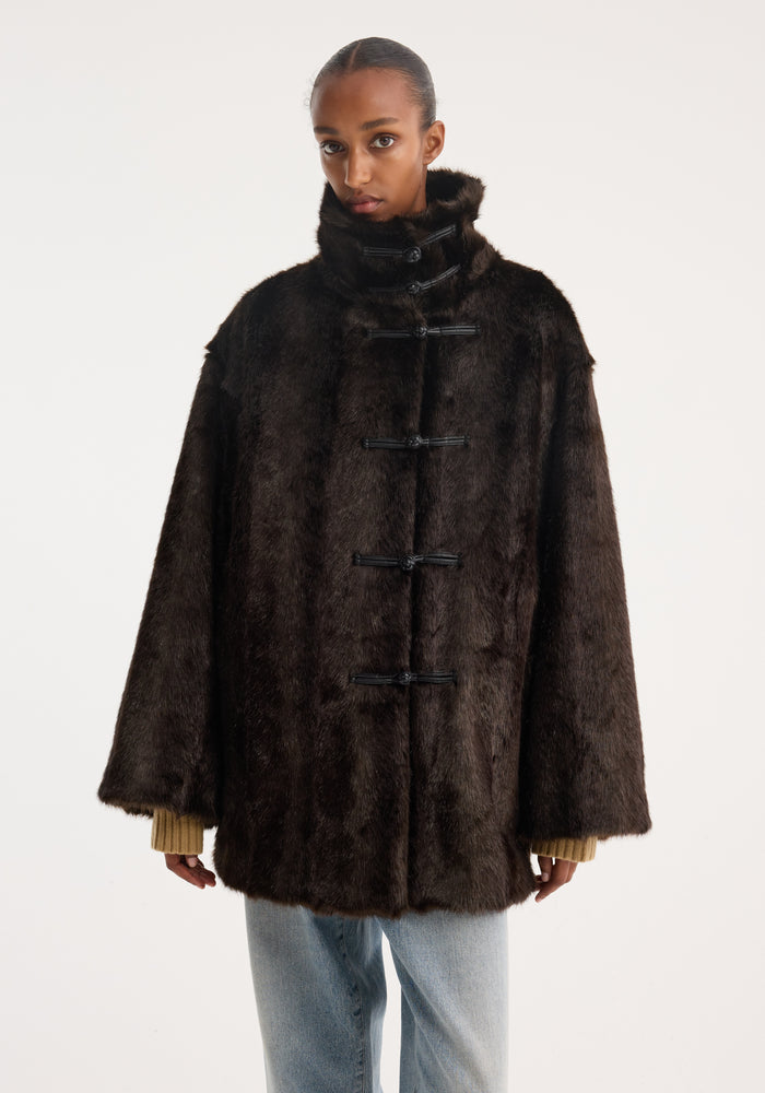 Model in Pankou closure faux fur short coat | dark brown, featuring a stand-up collar and pankou closures, over muted sweater and light-wash jeans.