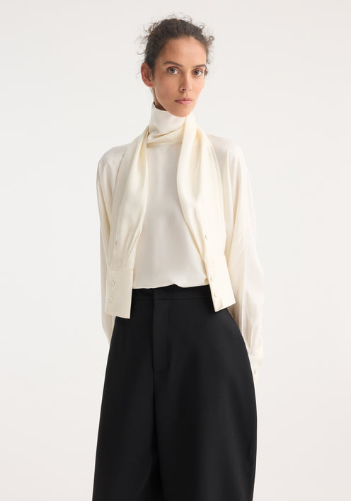 Model wearing Foulard silk top with draped sleeves, creating a scarf effect, paired with high-waisted black trousers and cream lace-up shoes.