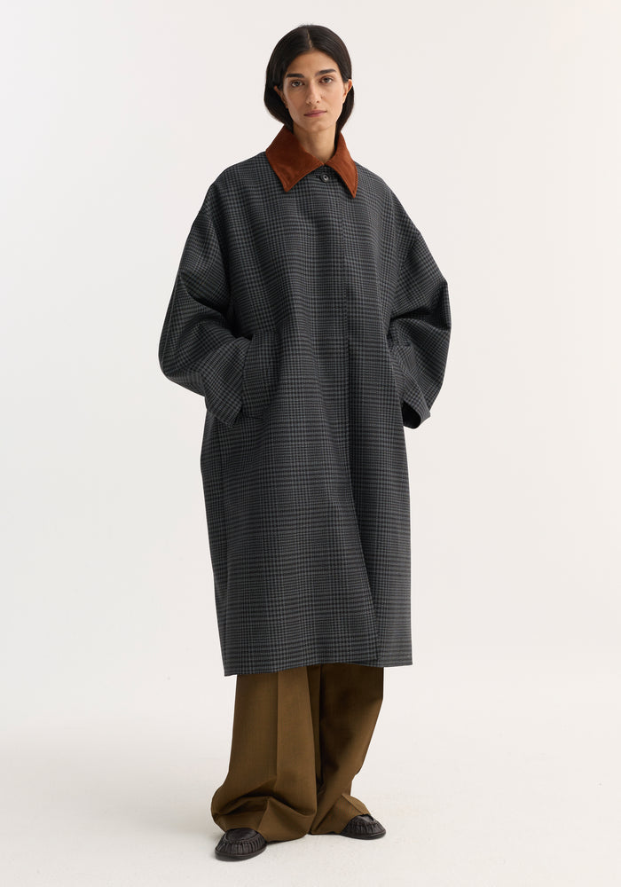 Model wearing a Suede collar check coat in black/grey, featuring an oversized fit, rust-brown suede collar, with slant pockets and wide-leg trousers.