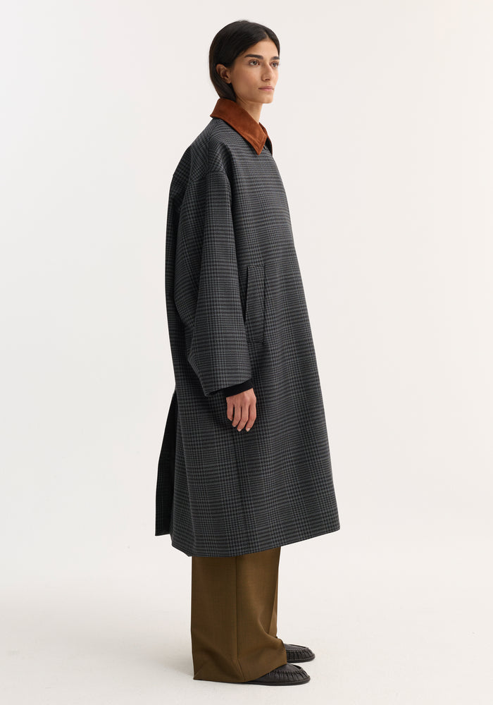 Person in profile wearing Suede Collar Check Coat, featuring oversized fit, dark check pattern, rust-brown suede collar, slant pockets, and concealed placket.