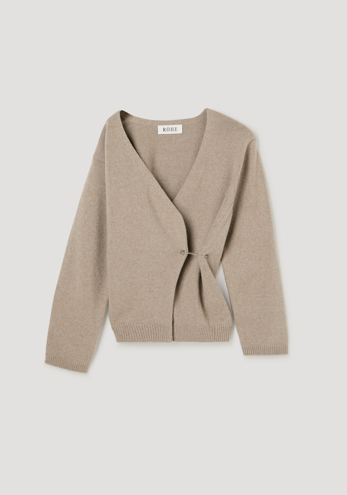 Off-shoulder wrap cardigan in light taupe, featuring a deep V-neck and long sleeves, crafted from a wool-cashmere blend with a safety-pin closure.
