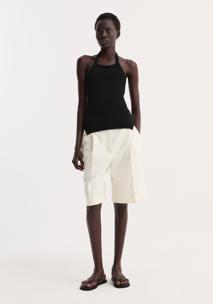 Chunky knit halter top | black, worn by a model, features a fitted design, side slits, and a neck button closure for comfort.