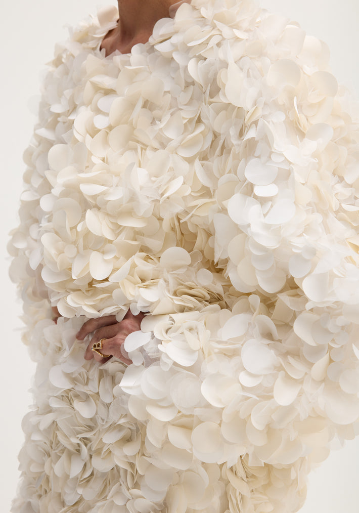 Handmade embellished jacket in ivory featuring overlapping fabric petals, showcasing a voluminous texture with a hook-and-eye closure at the neckline.