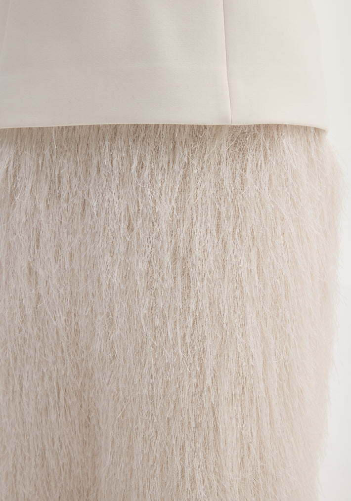 Close-up of the Fringe dress in ivory, featuring straw-like fibers forming a textured, full-length fringe skirt attached to a smooth fabric band.
