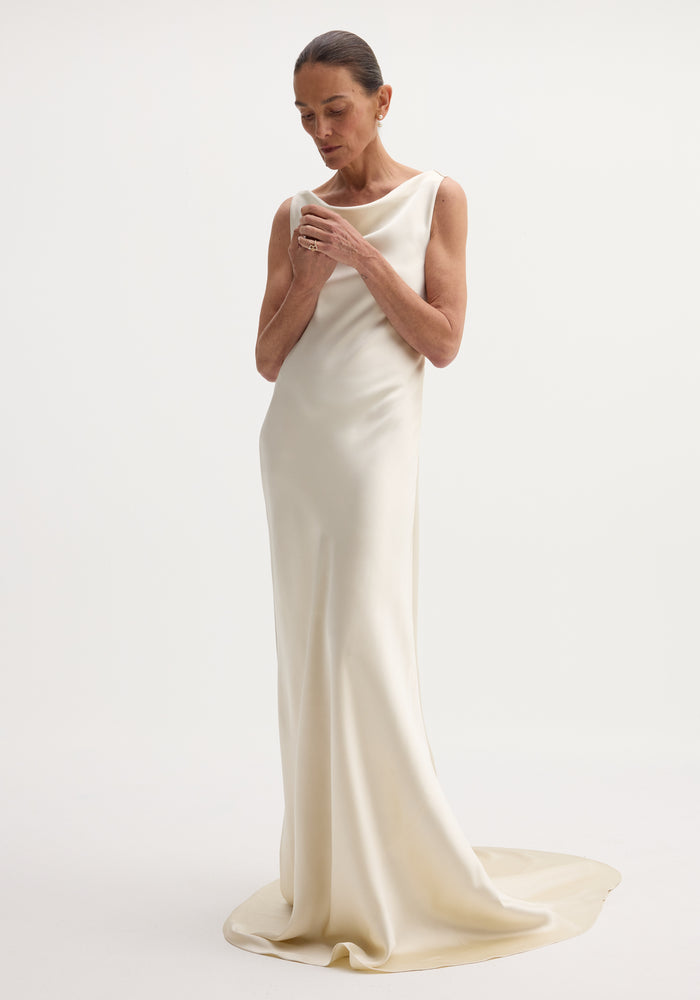 Draped satin dress with train | ivory: A sleeveless, floor-length gown with a bateau neckline, bias-cut for elegant drape, featuring a smooth column silhouette and elegant train.