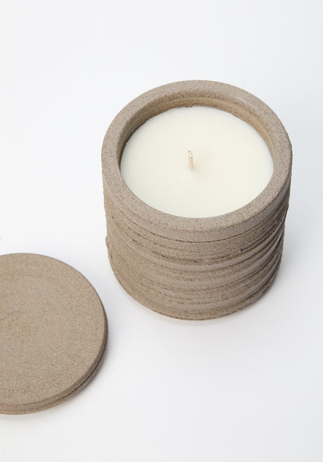 Stack of sand-colored discs on a woven mat, part of the Diplomatico Scented Candle set, featuring Róhe’s aromatic fragrance in a handmade ceramic vessel.