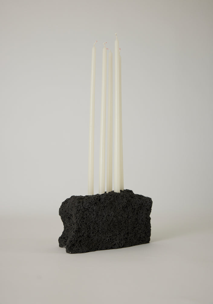 Sculptural Stone Candle Holder with seven lit taper candles on a white plinth, handcrafted from lava stone by Dutch artist Louis Crombag.