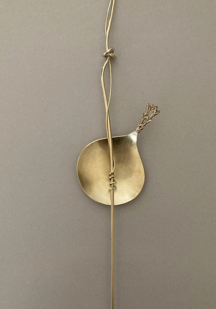 Tea Spoon: A brass-colored scoop with a textured handle, wire-wrapped to a slender rod, showcasing Misae Nikkei's handcrafted artistry from Kyoto.