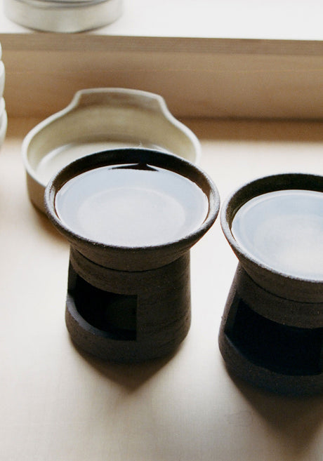 Ceramic Oil Burner | soil: A two-piece brown ceramic burner with a signature carved finish, paired with a 20 ml Róhe Diplomatico scented oil bottle.