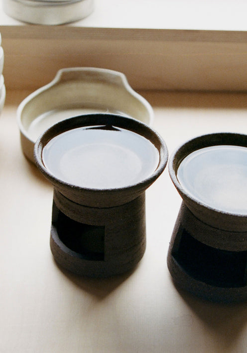 Ceramic Oil Burner | soil: A two-piece brown ceramic burner with a signature carved finish, paired with a 20 ml Róhe Diplomatico scented oil bottle.