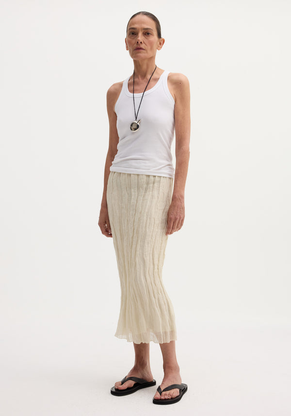 Model wearing a Textured tube skirt | cream, featuring a crinkled, mid-calf length design with an elasticated waistband, styled with a rib-knit tank top.
