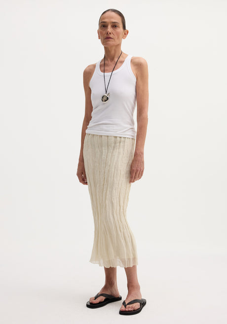 Model wearing a Textured tube skirt | cream, featuring a crinkled, mid-calf length design with an elasticated waistband, styled with a rib-knit tank top.