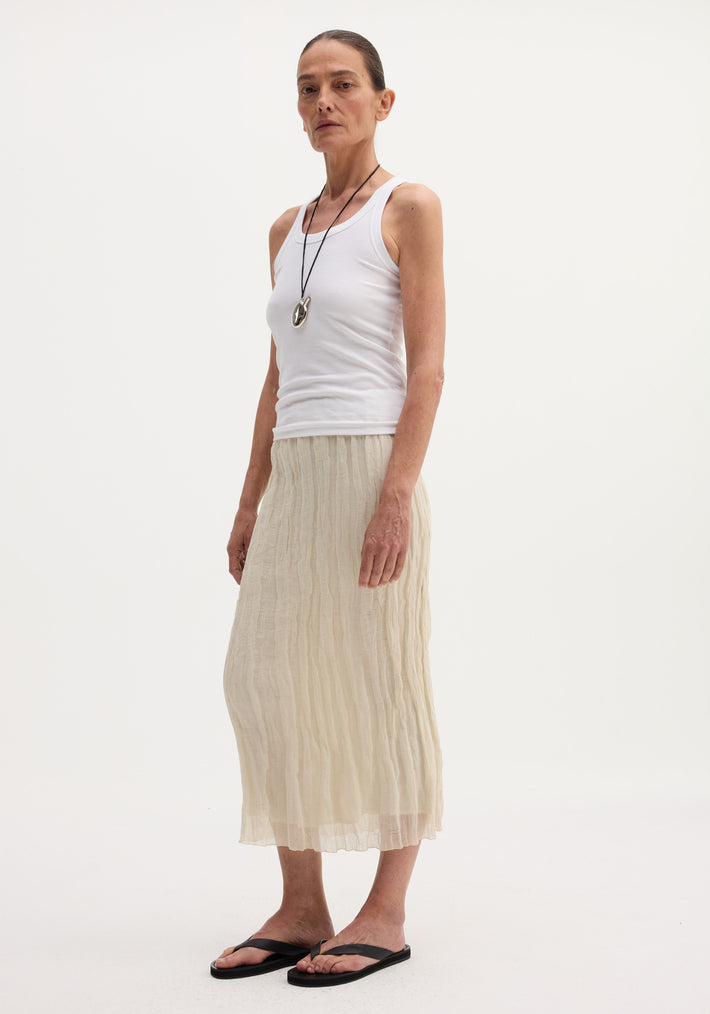Textured tube skirt in cream, featuring a straight silhouette, mid-calf length, and elastic waistband, worn by a tall model with a rib-knit tank top.