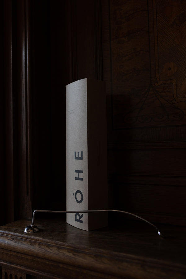 Candle Stopper | silver, a sleek, curved stainless steel tool with a spiraling handle, rests elegantly on dark wood, ideal for safely extinguishing candles.