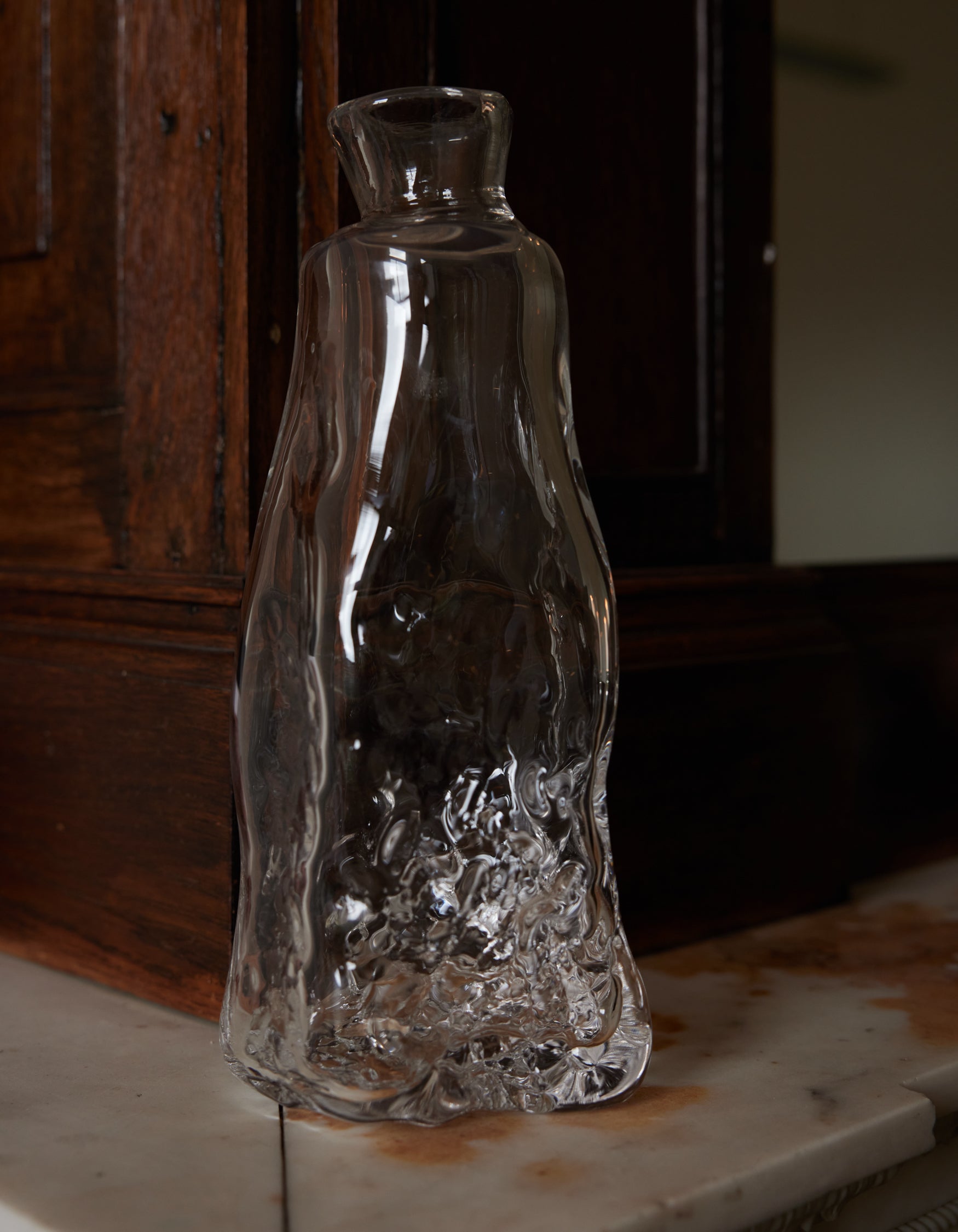 Blown vase | Glass: A free-form clear-glass vessel with fluid, sculptural contours, reflecting light on a marble surface, embodying Szkło Studio's unique craftsmanship.