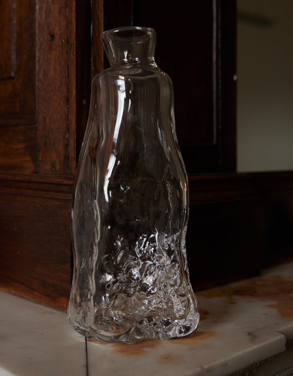Blown vase | Glass: A free-form clear-glass vessel with fluid, sculptural contours, reflecting light on a marble surface, embodying Szkło Studio's unique craftsmanship.