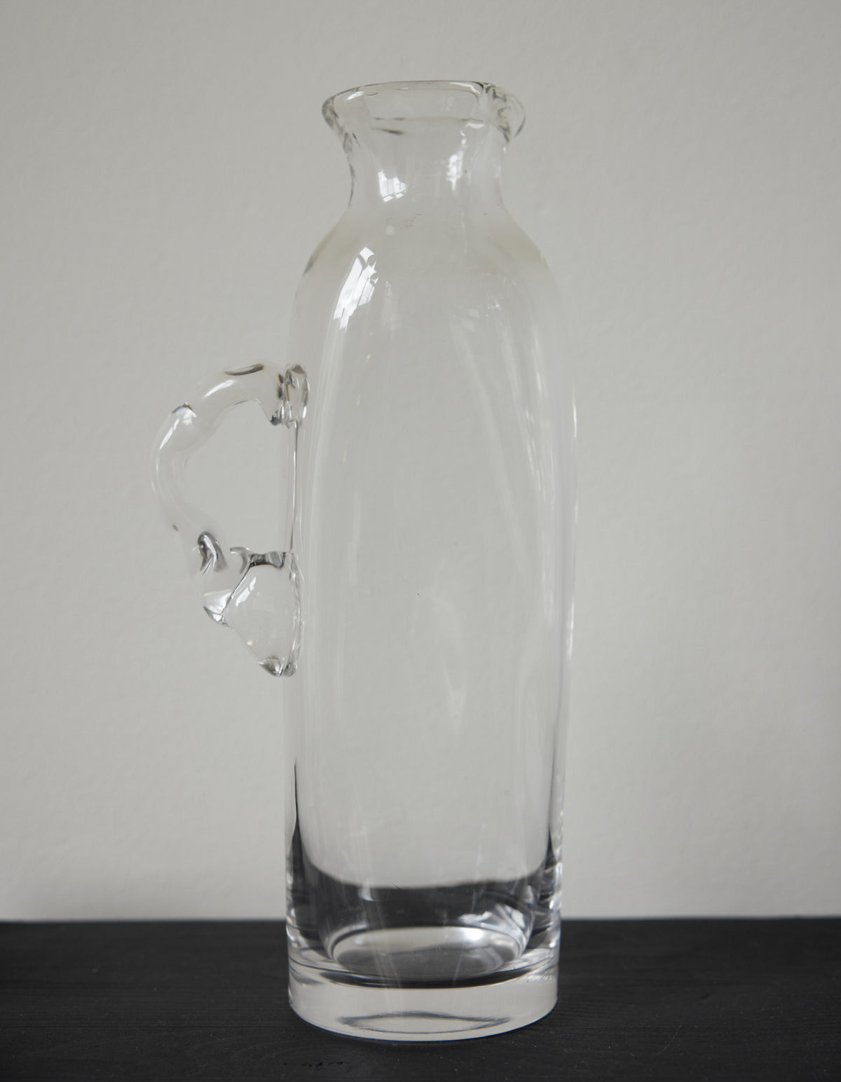 Large water carafe | Glass: A tall, clear glass vessel with a unique, irregular handle, showcasing Szkło Studio's experimental, hand-blown craftsmanship.