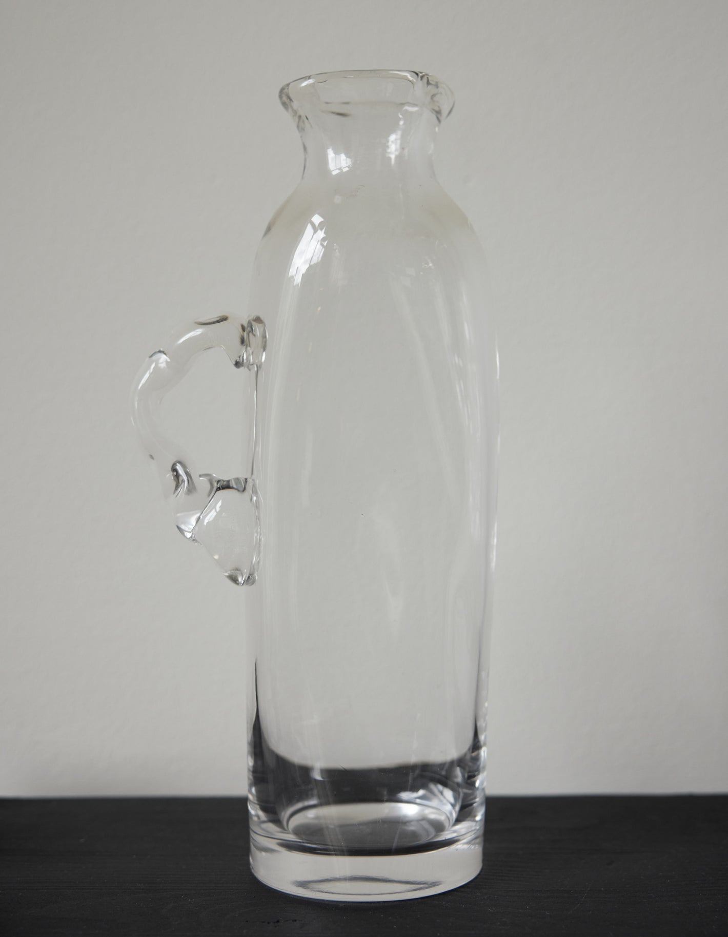 Large water carafe | Glass: A tall, clear glass vessel with a unique, irregular handle, showcasing Szkło Studio's experimental, hand-blown craftsmanship.