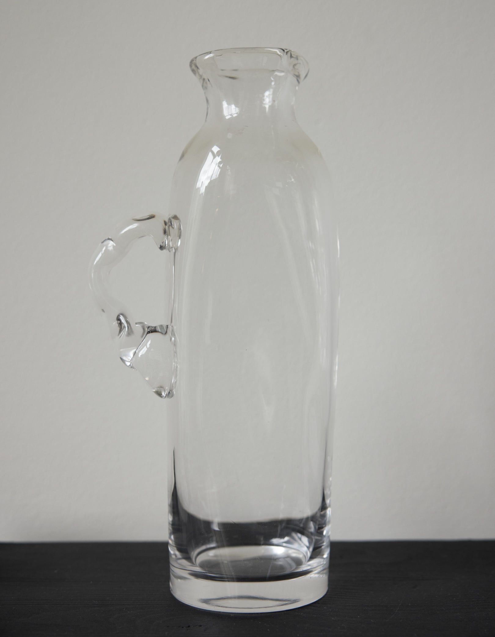 Large water carafe | Glass: A tall, clear glass vessel with a unique, irregular handle, showcasing Szkło Studio's experimental, hand-blown craftsmanship.