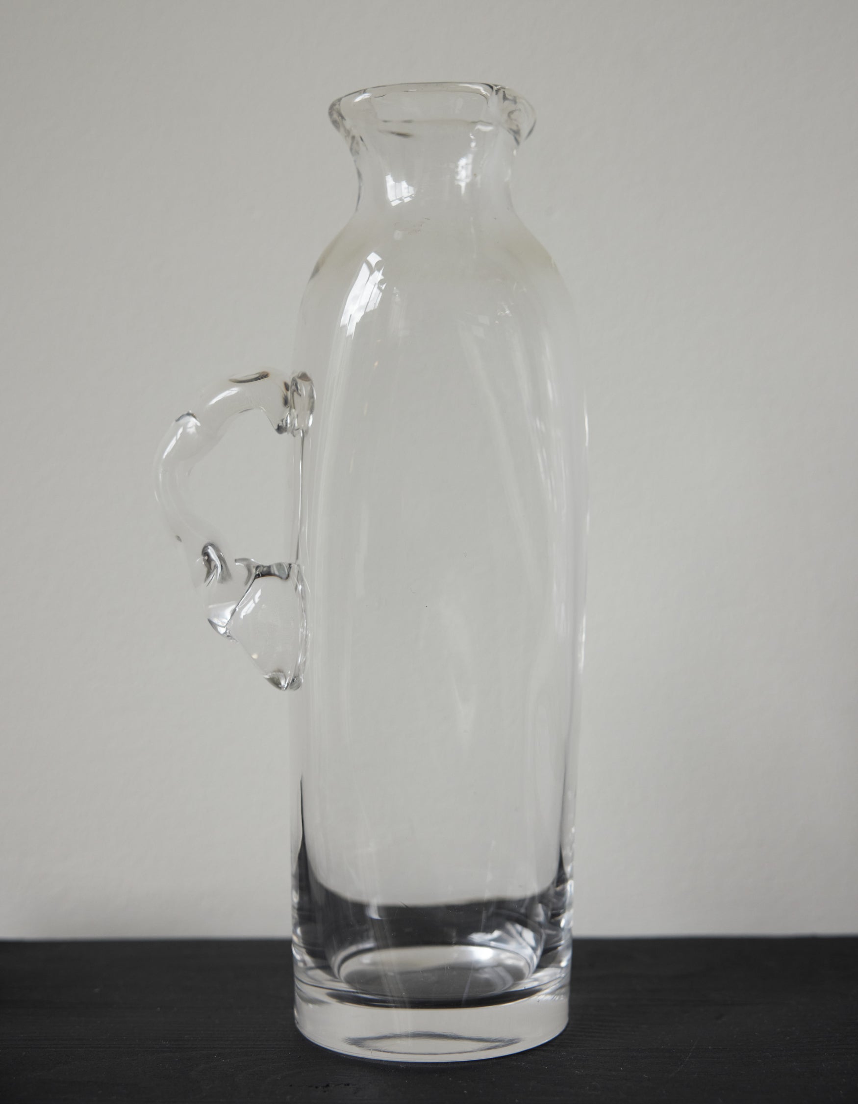 Large water carafe | Glass: A tall, clear glass vessel with a unique, irregular handle, showcasing Szkło Studio's experimental, hand-blown craftsmanship.