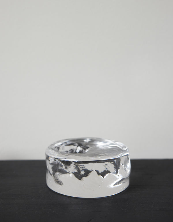 Presse-papier & holder | Glass: A small, polished silver metal object with a melted texture and shallow dish top, showcasing minimalist, sculptural design.
