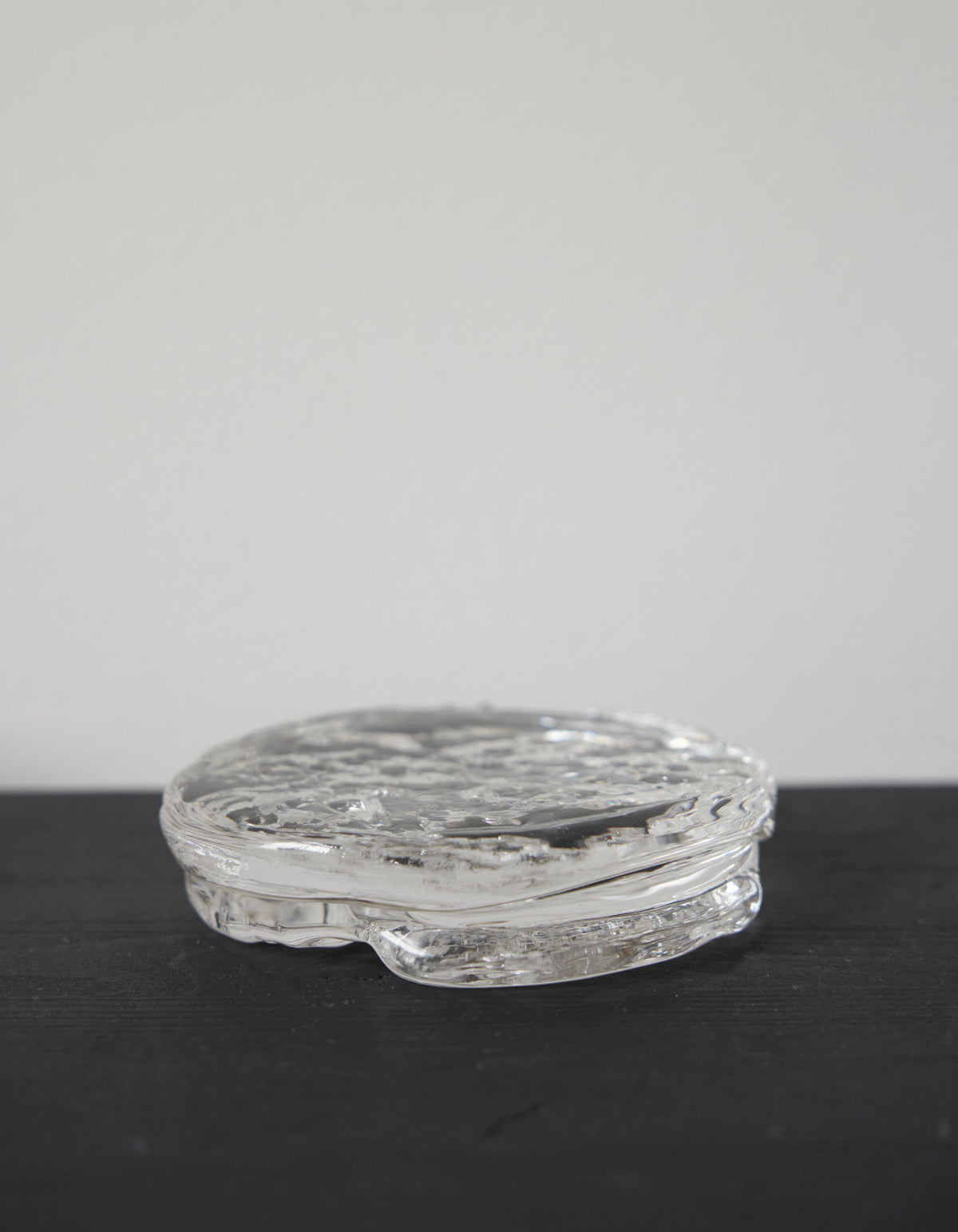 Butter plate | Glass: A round, clear glass piece with a rippled, organic texture, showcasing Szkło Studio's unique hand-blown craftsmanship and artistic design approach.