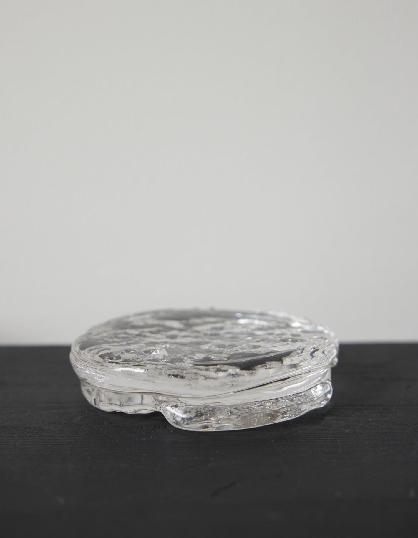 Butter plate | Glass: A round, clear glass piece with a rippled, organic texture, showcasing Szkło Studio's unique hand-blown craftsmanship and artistic design approach.