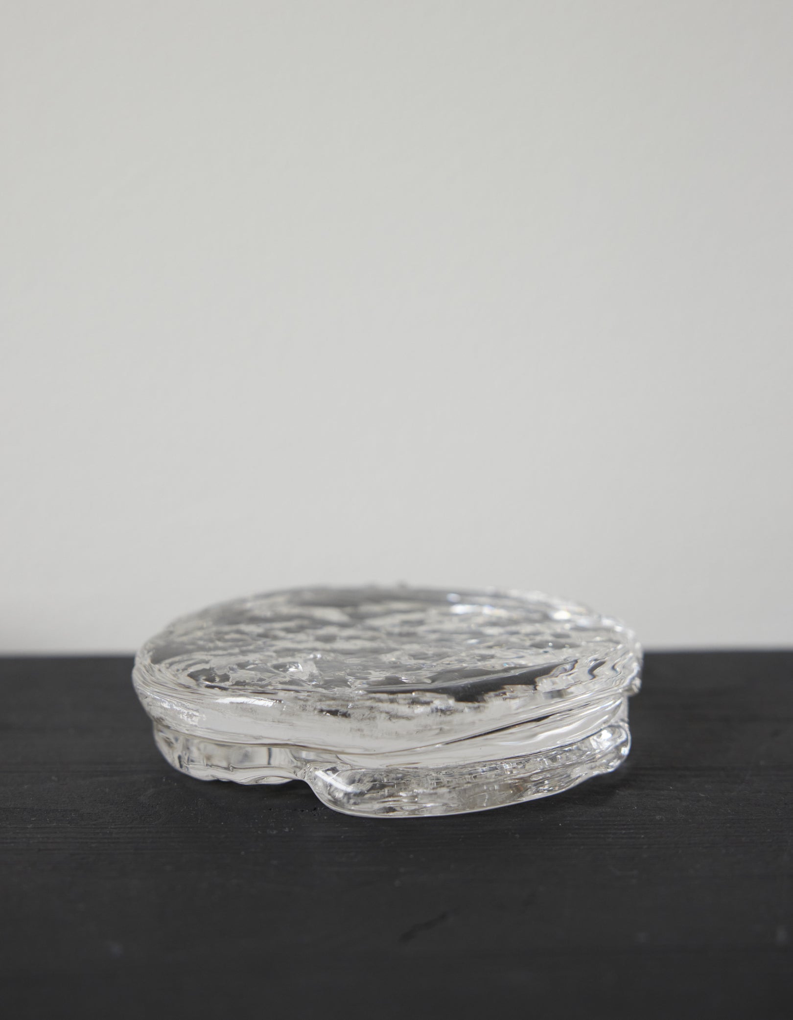 Butter plate | Glass: A round, clear glass piece with a rippled, organic texture, showcasing Szkło Studio's unique hand-blown craftsmanship and artistic design approach.