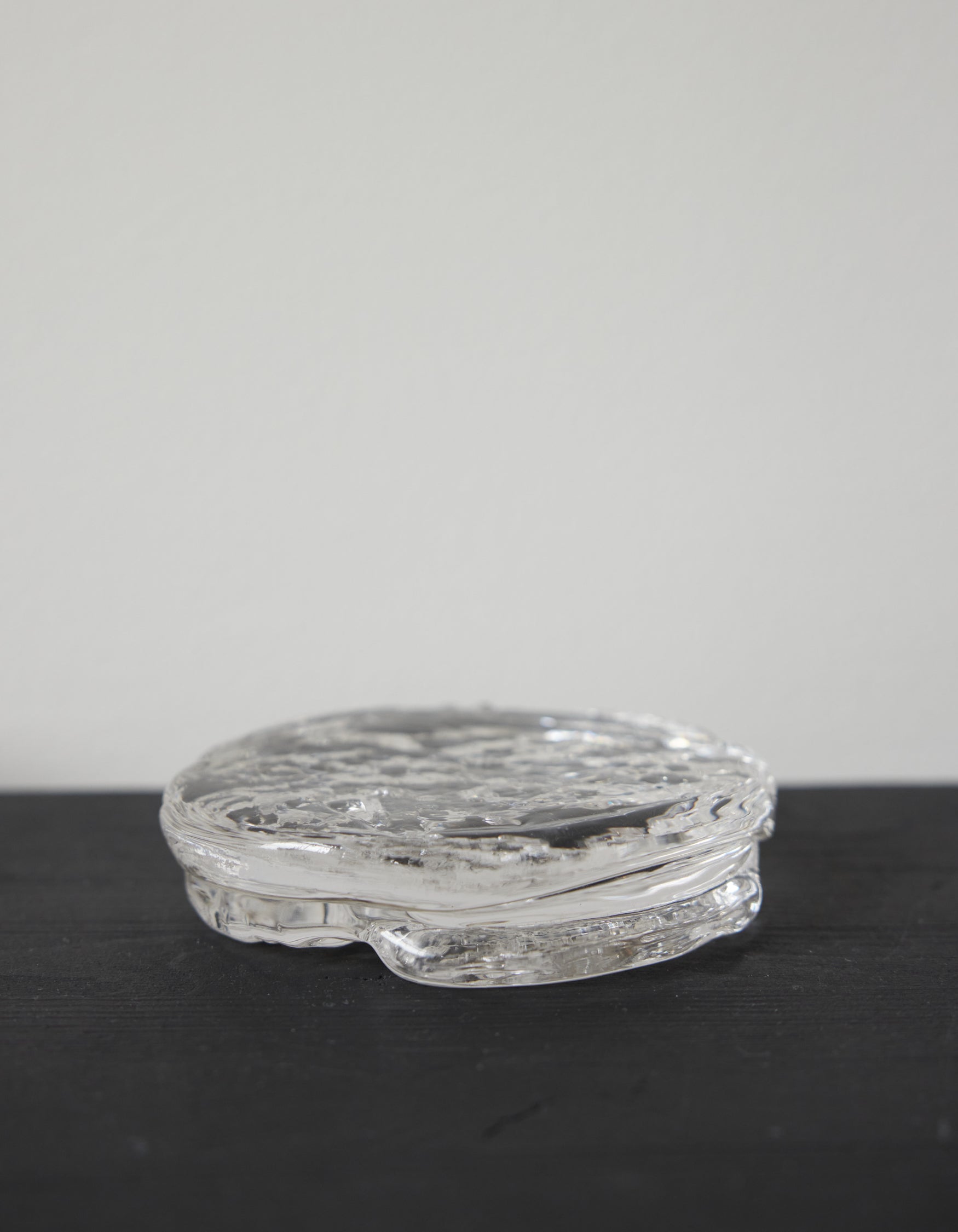 Butter plate | Glass: A round, clear glass piece with a rippled, organic texture, showcasing Szkło Studio's unique hand-blown craftsmanship and artistic design approach.