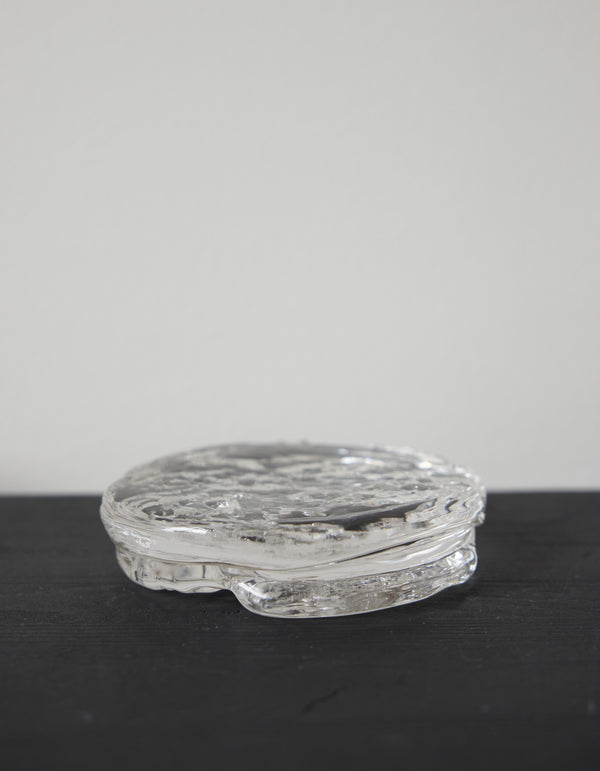 Butter plate | Glass: A round, clear glass piece with a rippled, organic texture, showcasing Szkło Studio's unique hand-blown craftsmanship and artistic design approach.