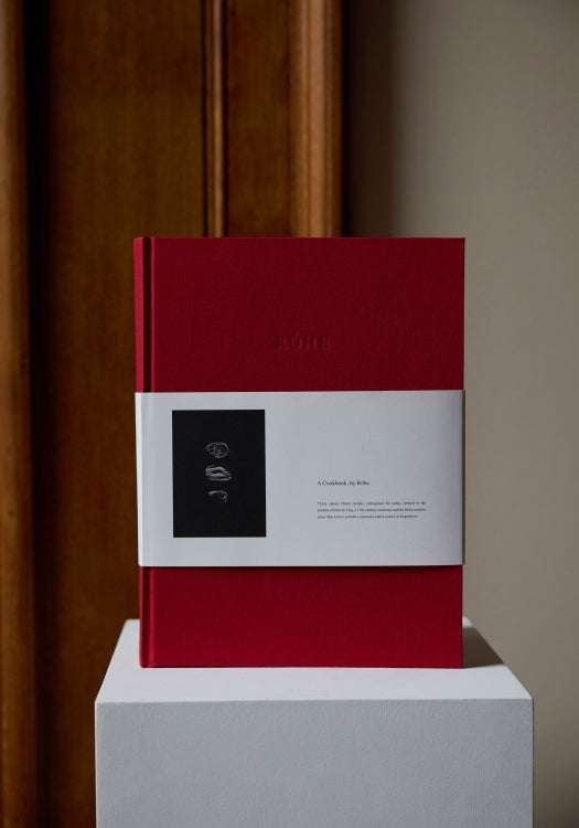 Róhe Cookbook | red, cloth-bound hardcover with a white sleeve featuring mushroom sketches and “A Cookbook by Röhe,” highlighting 30 reimagined Dutch recipes.
