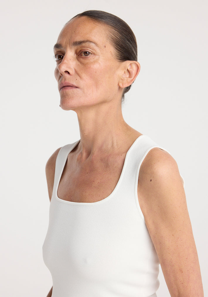 Woman wearing a sleeveless white fitted top with a square neckline, styled in a bustier shape, titled Bustier shaped knitted top | optic white.