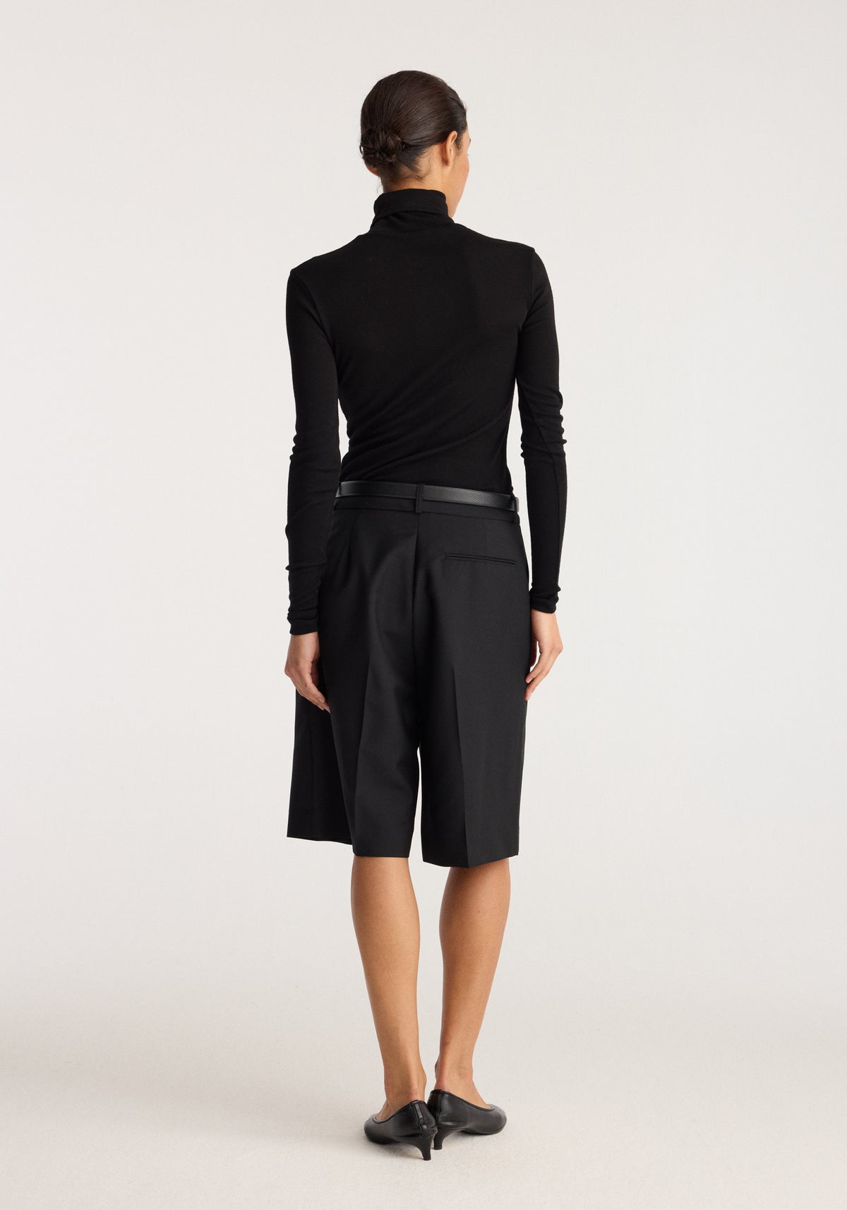Fine merino turtleneck | black shown from the back on a model with a fitted silhouette long sleeves and a high neck in smooth black knit fabric
